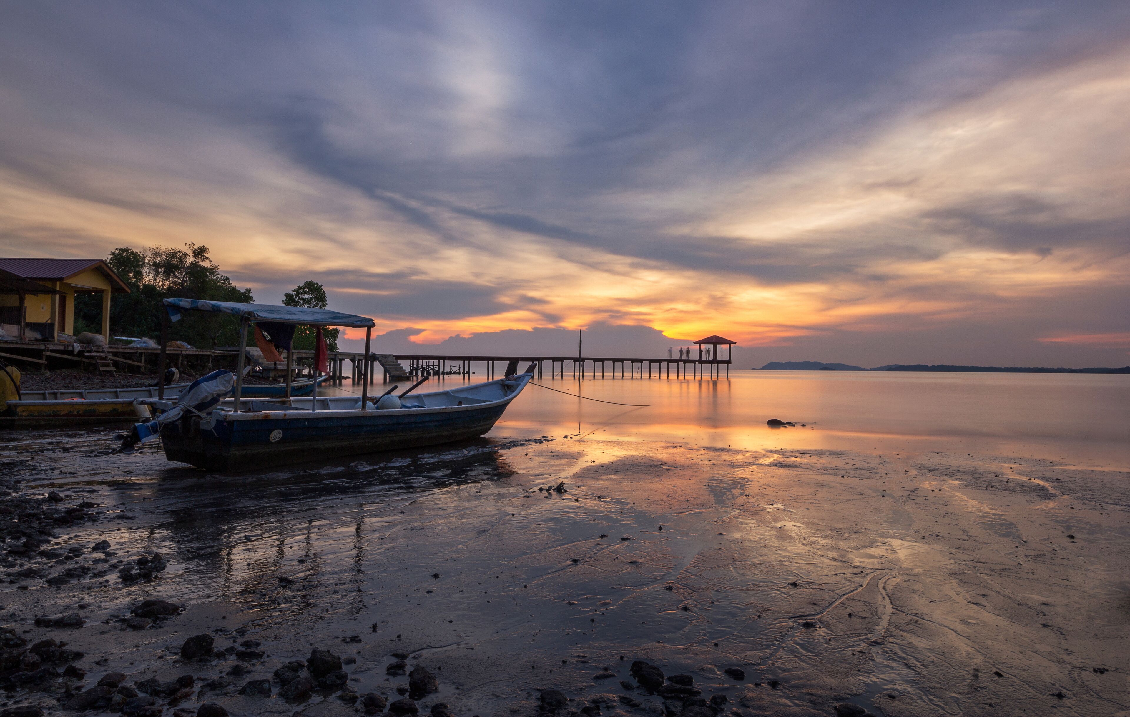 A boat docked at a pier with a sunset in the background.