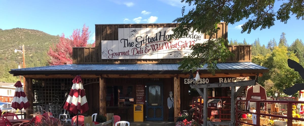 A rustic gift shop with a sign reading "The Gifted Horse Lodge Gourmet Deli & Wild West Gift Box."