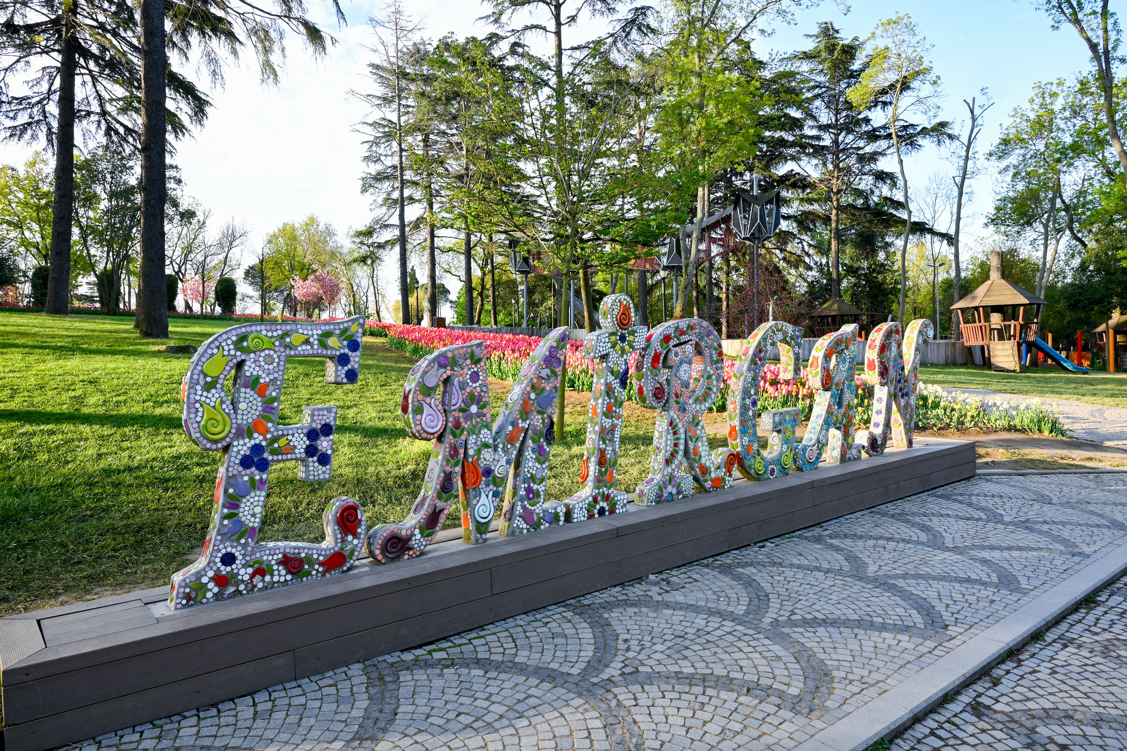 A park with a mosaic sculpture spelling 'EASTGON' and a playground in the background.