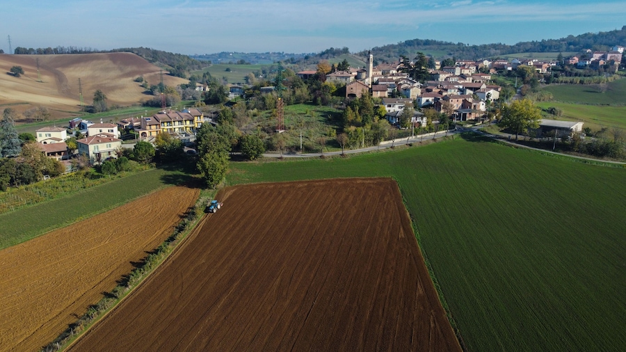 Ländliche Landschaft mit Feldern, einem Dorf und einem Kirchturm.
