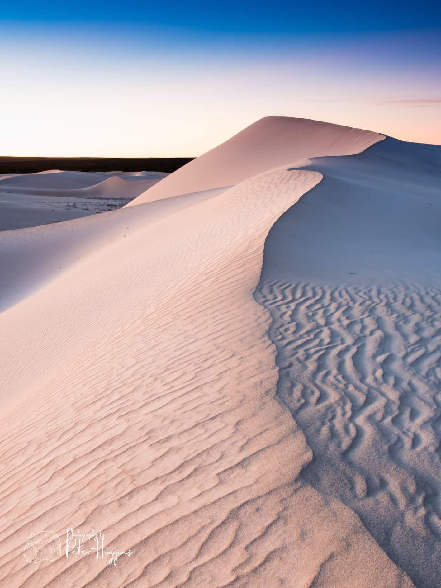 A desert landscape with sand dunes and a clear sky.