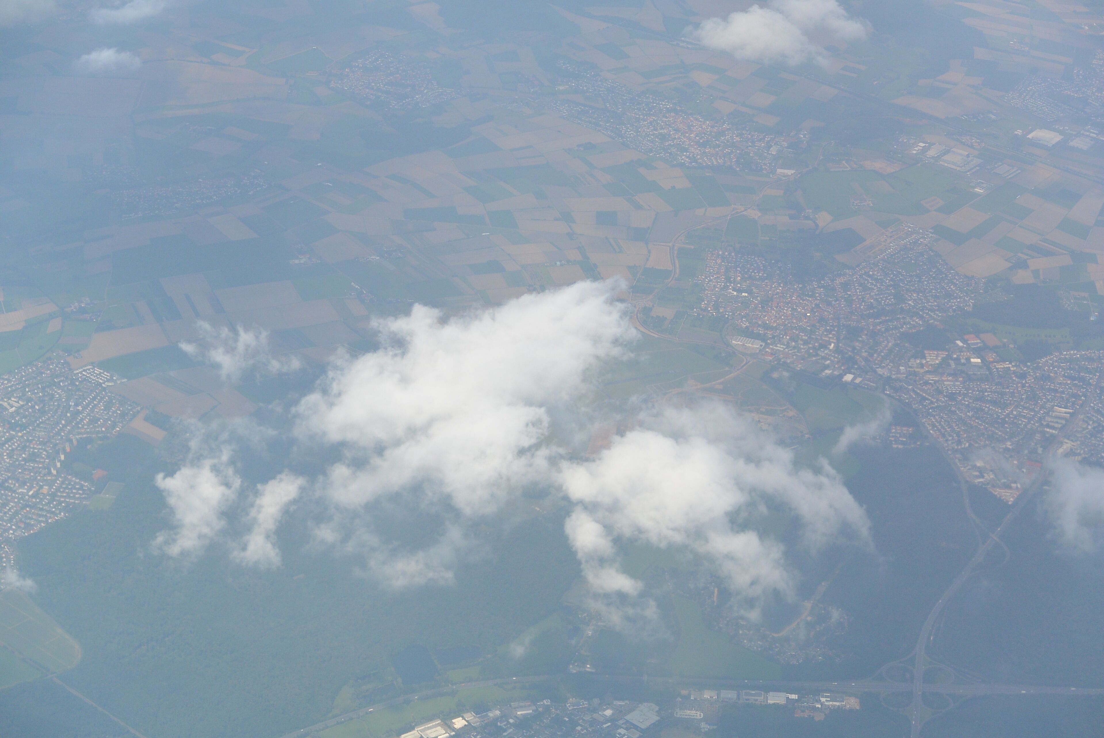 An aerial view of a landscape with fields, a town, and a body of water.