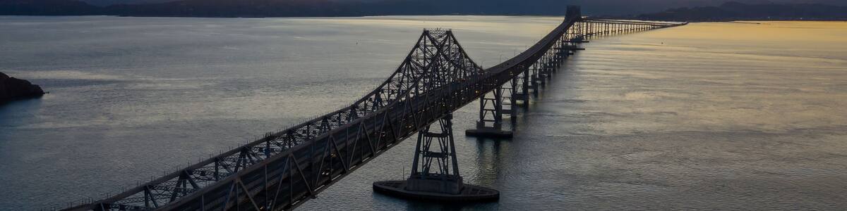 The Richmond-San Rafael Bridge spans San Pablo Bay in Richmond, California, USA, connecting counties. Cars travel across at sunset.