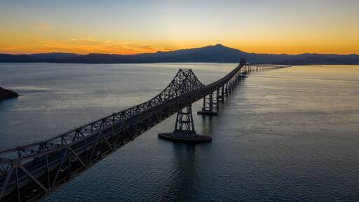 The Richmond-San Rafael Bridge spans San Pablo Bay in Richmond, California, USA, connecting counties. Cars travel across at sunset.