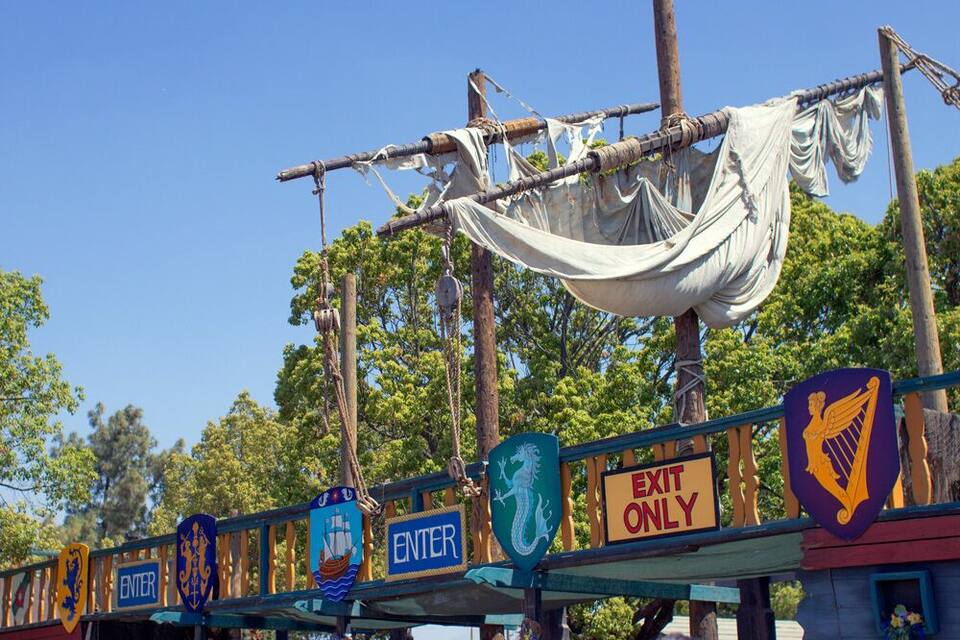 A wooden bridge with 'ENTER' and 'EXIT ONLY' signs, and a dragon emblem.