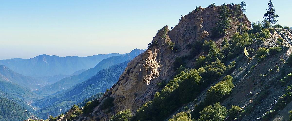 A mountainous landscape with dense forests and rocky cliffs.