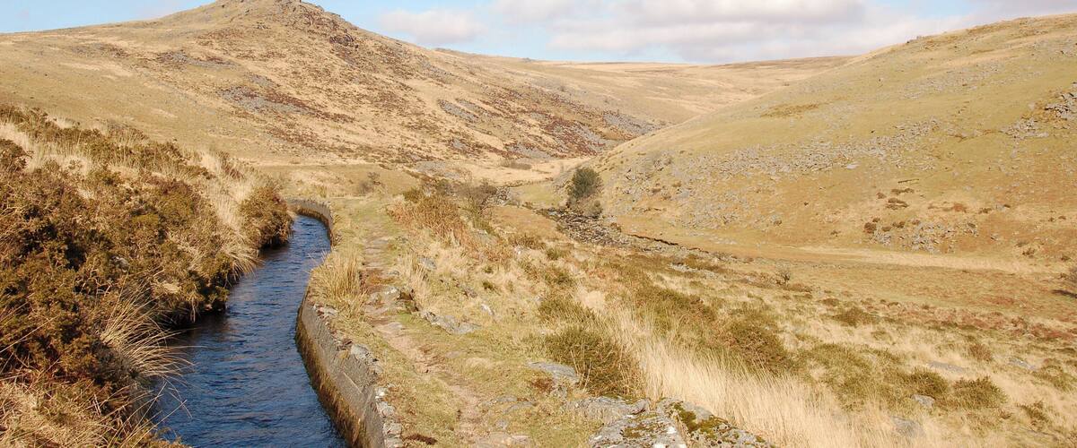 A river winding through a hilly landscape with sparse vegetation and a clear sky.
