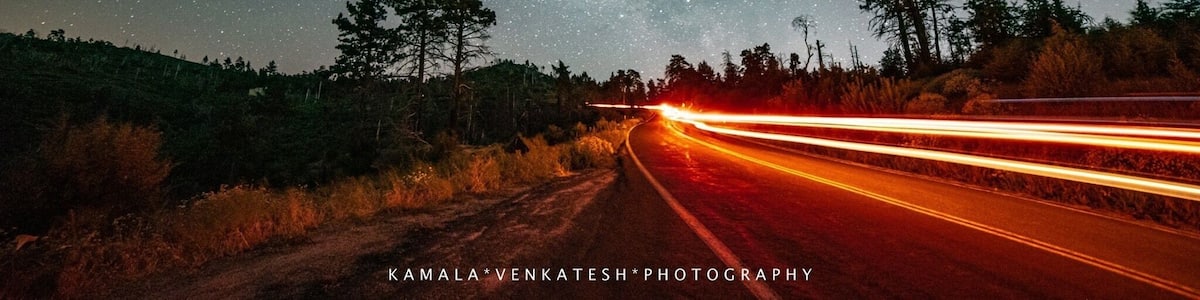 Un ciel étoilé au-dessus d’une route où l’on aperçoit des traînées de lumière.