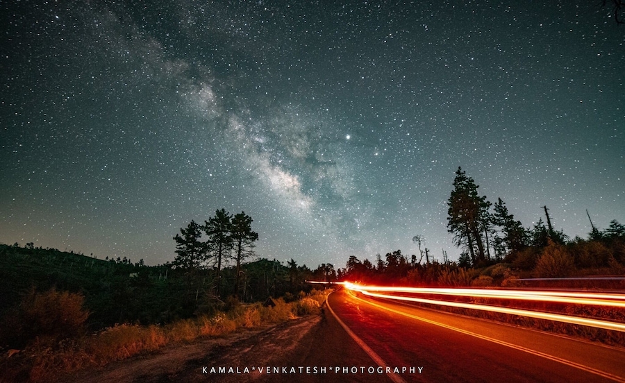 Cielo estrellado sobre una carretera con estelas de luz.