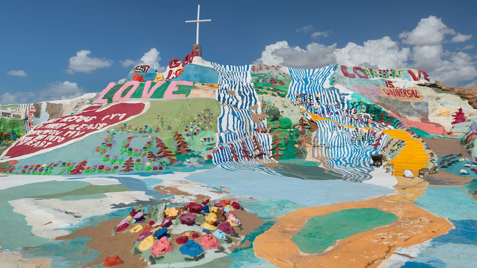 A colorful mural with a cross, text, and abstract patterns.
