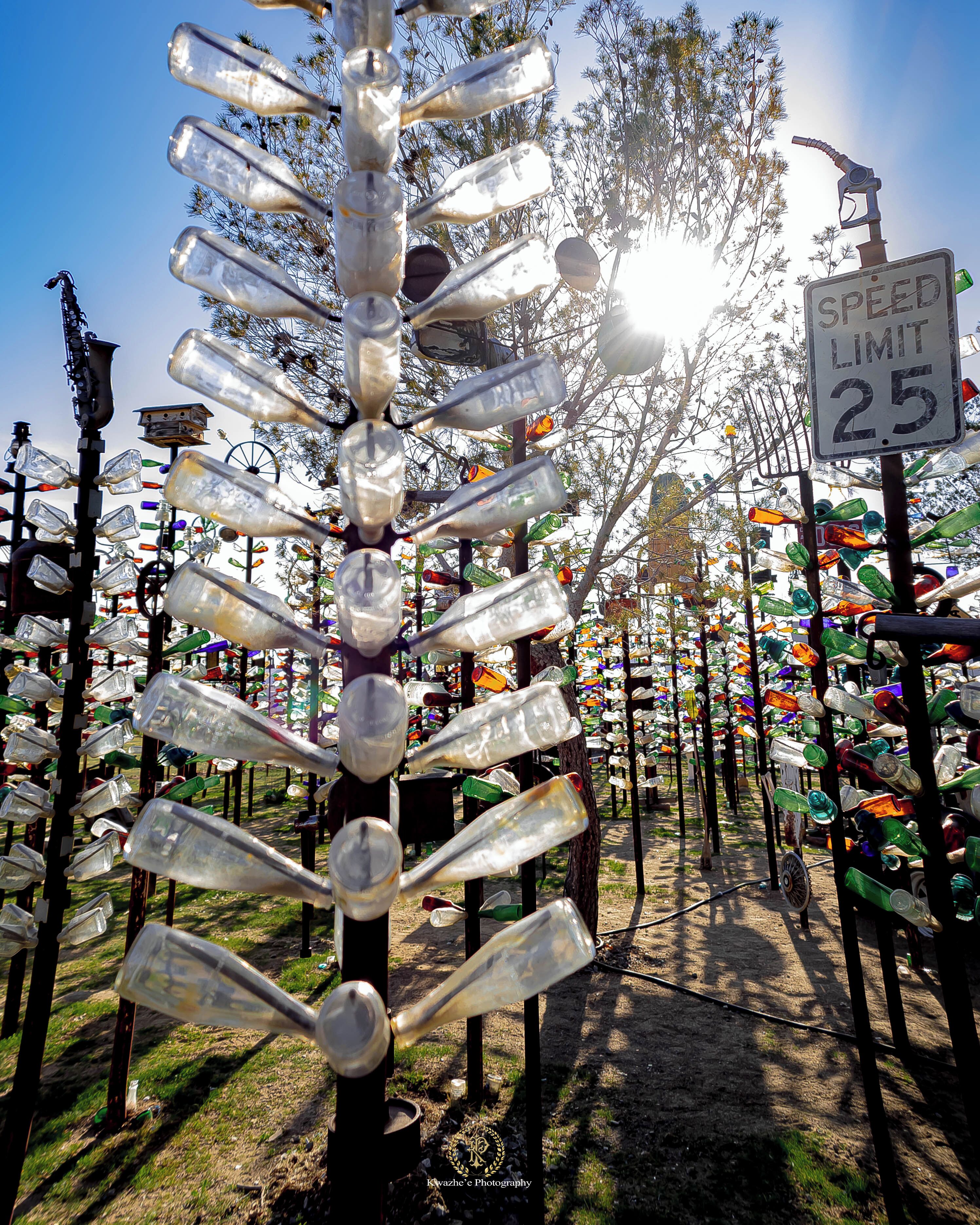 A sculpture made of recycled glass bottles, with a speed limit sign in the background.