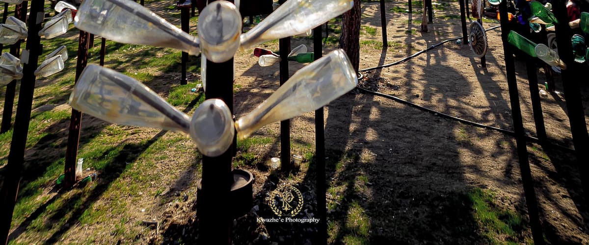 A sculpture made of recycled glass bottles, with a speed limit sign in the background.