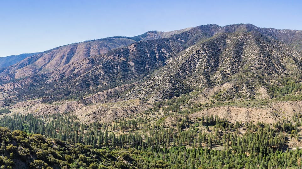 A mountainous landscape with dense forests and rugged terrain.