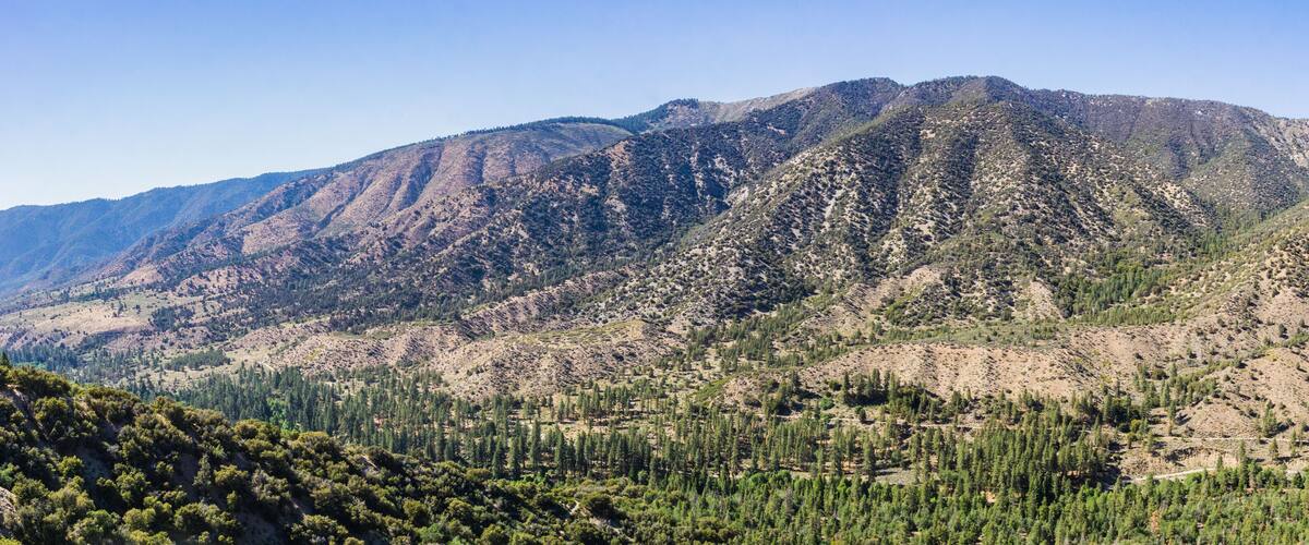 A mountainous landscape with dense forests and rugged terrain.