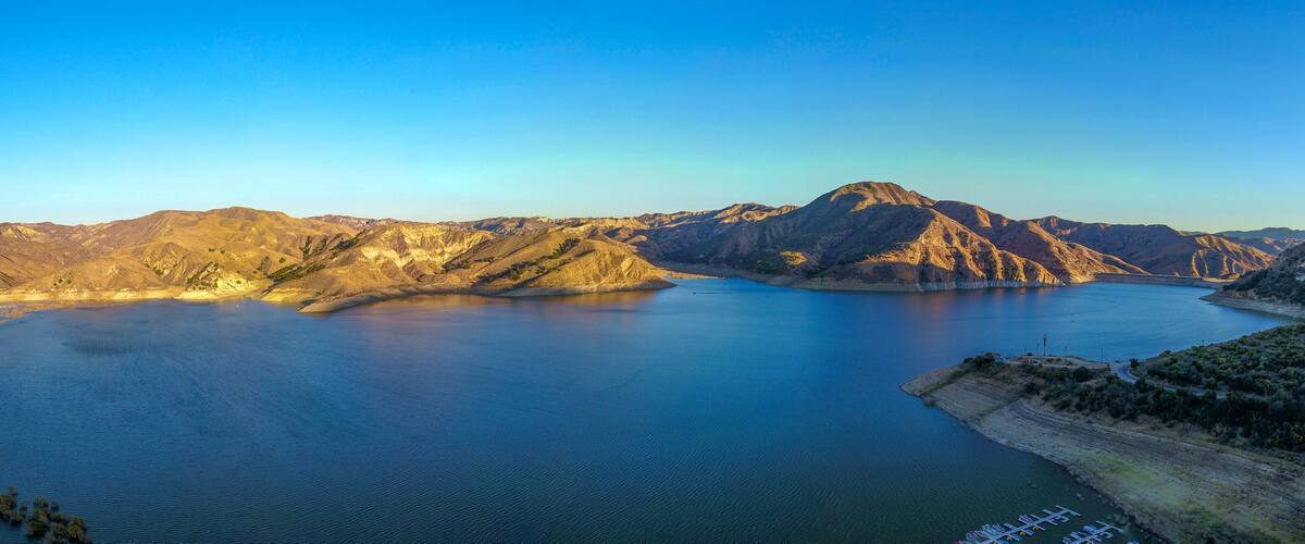 a stunning aerial shot of the deep blue lake water and mountains at Lake Piru in the Los Padres National Forest in California