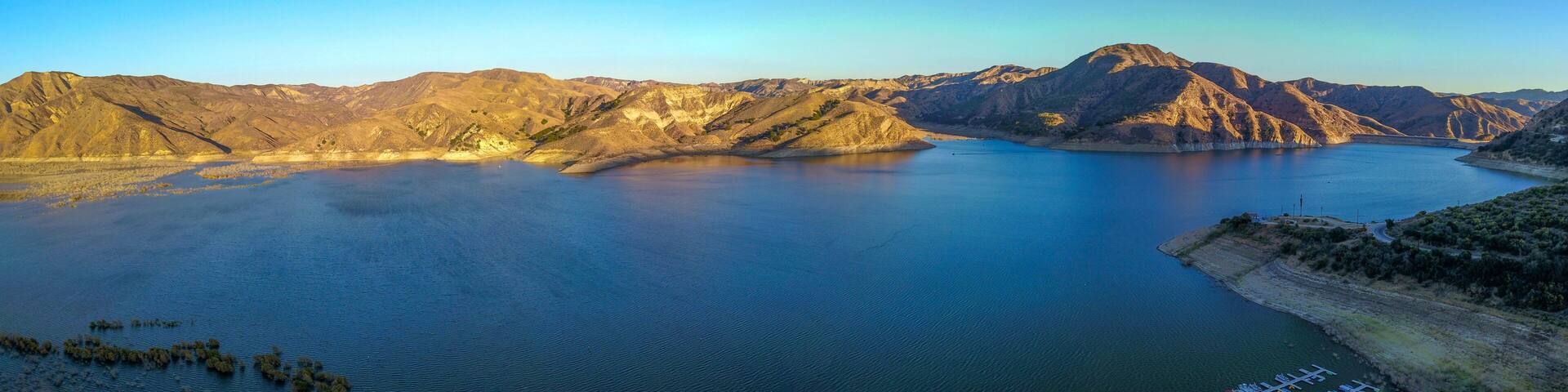a stunning aerial shot of the deep blue lake water and mountains at Lake Piru in the Los Padres National Forest in California