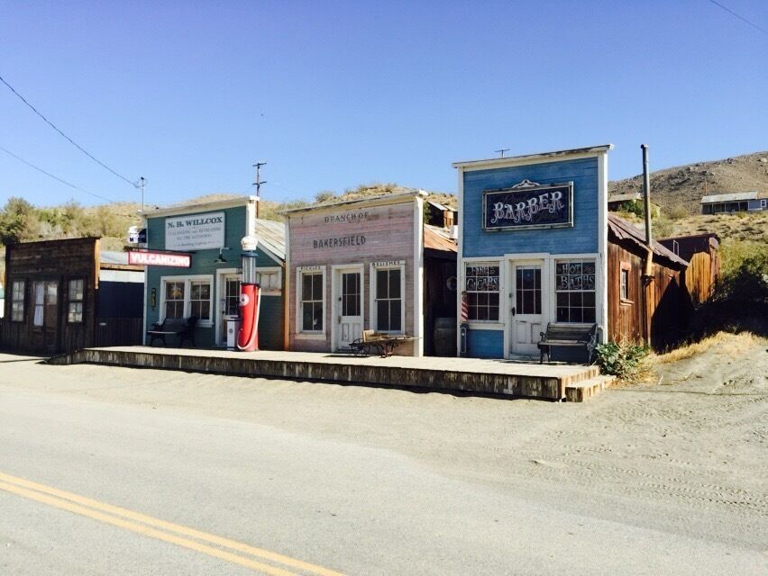 A row of old-fashioned buildings with signs for a barber, bakery, and other businesses.
