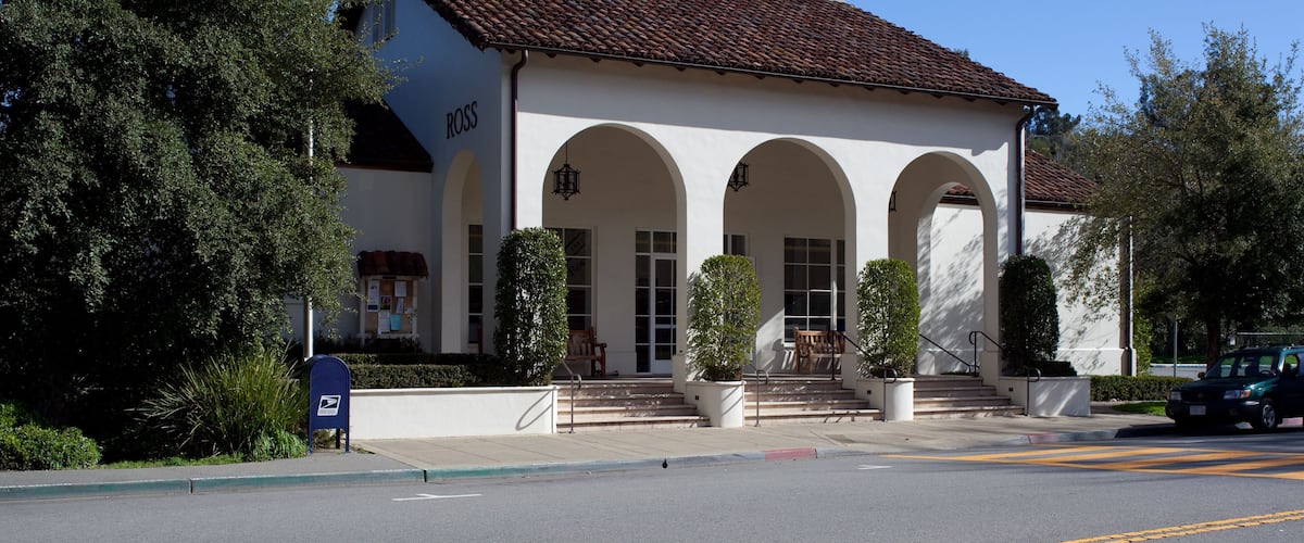 A white building with a red-tiled roof and arched windows.