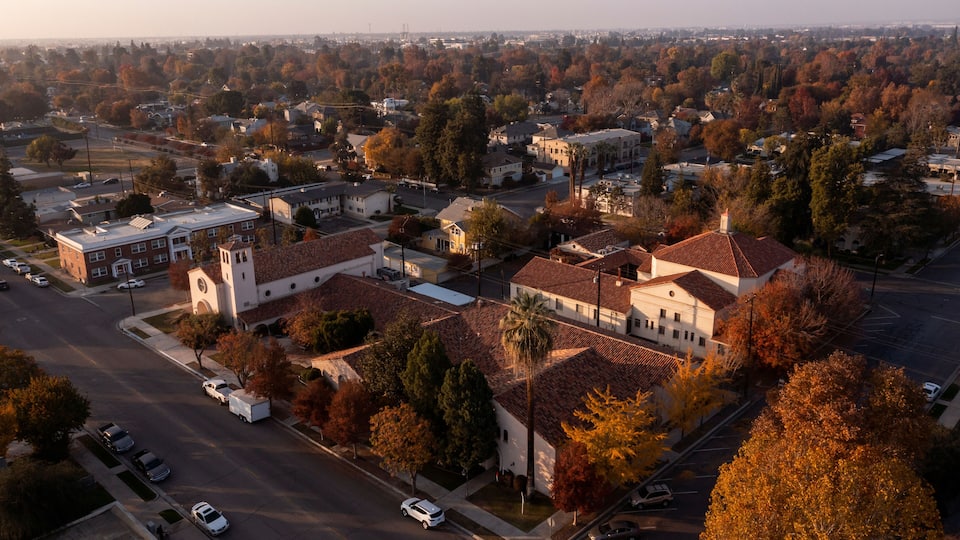 A residential area with a church, parked cars, and autumn foliage.