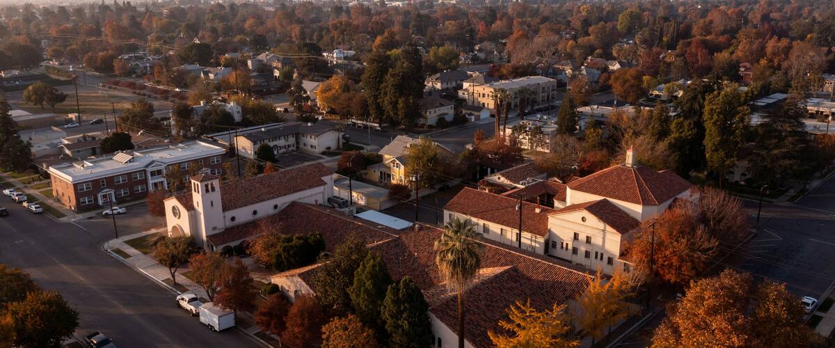 A residential area with a church, parked cars, and autumn foliage.