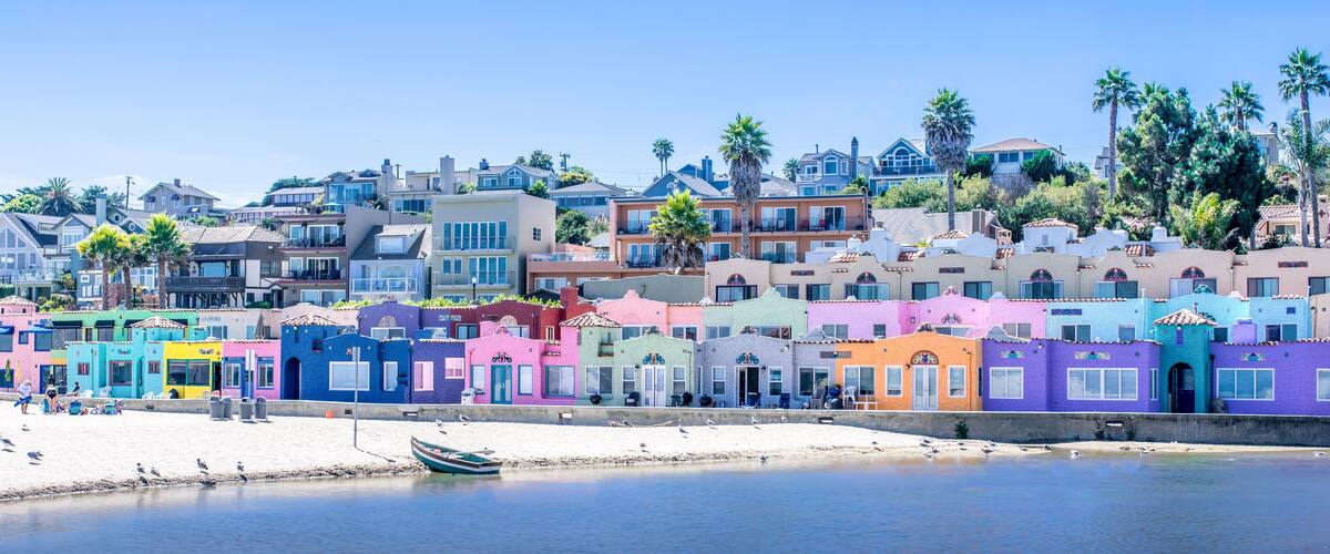 A colorful coastal town with pastel-colored buildings, a sandy beach, and a calm sea.