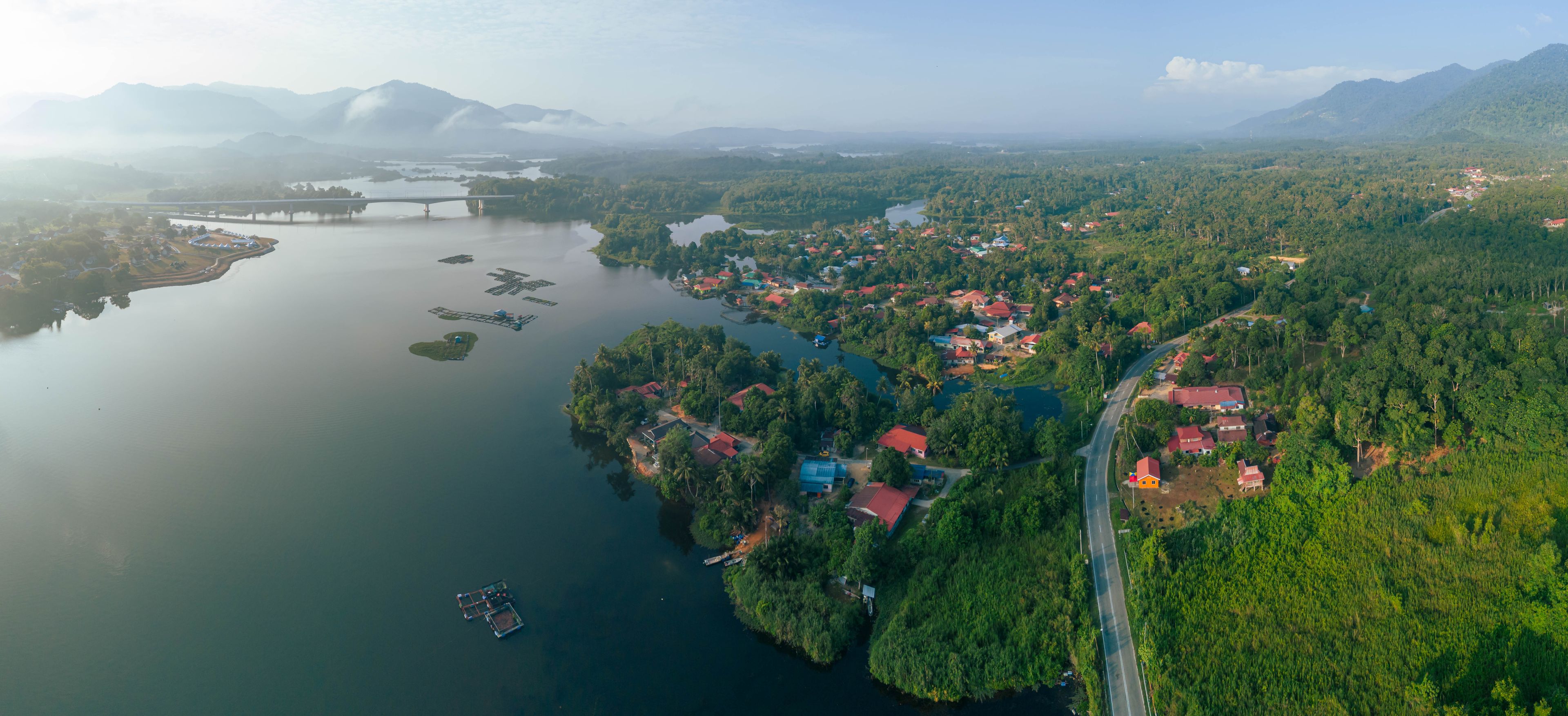 An aerial view of a coastal town with a bridge, a river, and surrounding greenery.