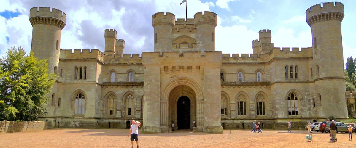 A historic castle with a large entrance, two towers, and a flag on top.
