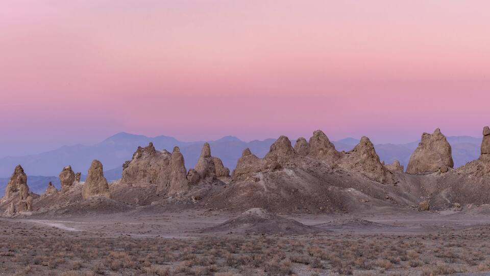 A desert landscape with unique rock formations and distant mountains.