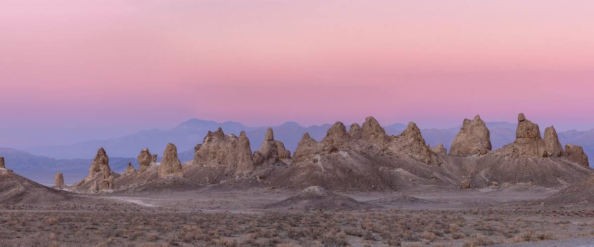 A desert landscape with unique rock formations and distant mountains.