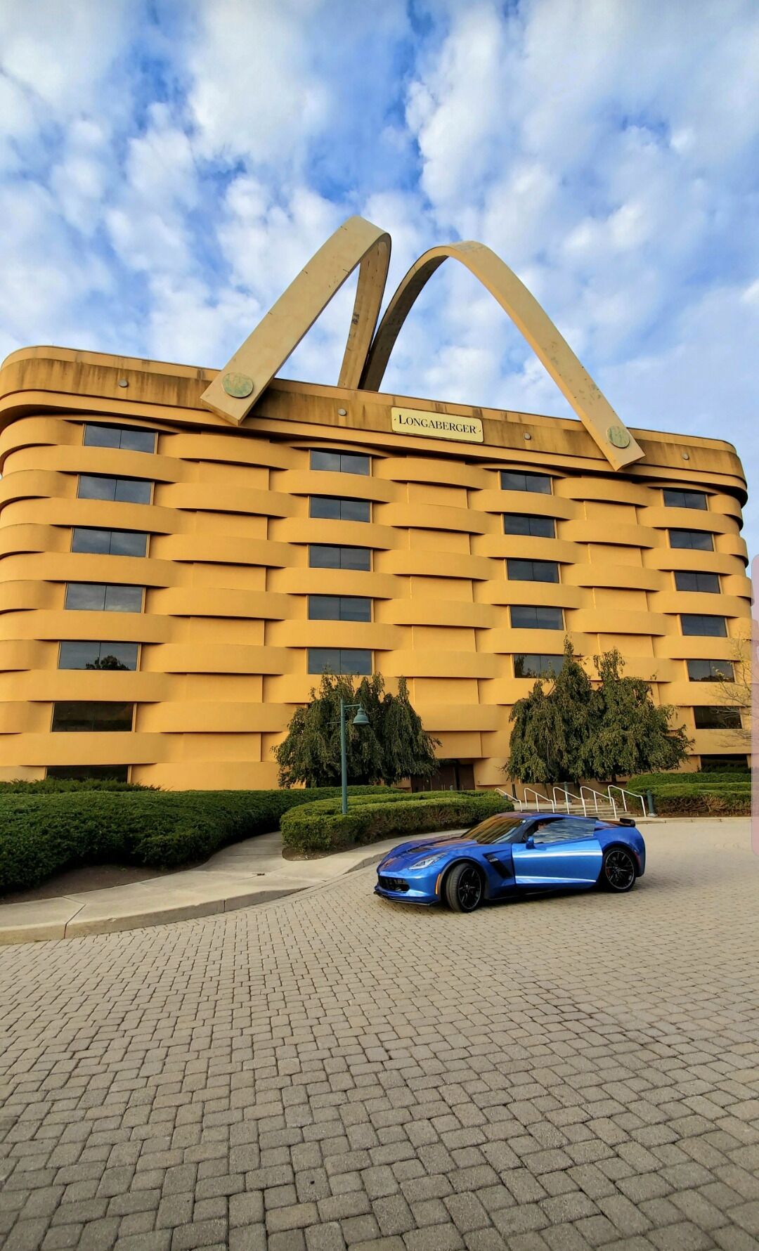 A yellow building with a sign reading "Longaberger" and a blue sports car parked in front.
