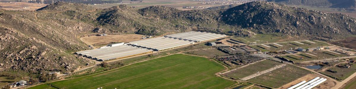 Un vaste complexe industriel comprenant de nombreux entrepôts et des réservoirs de stockage, situé dans une région montagneuse.