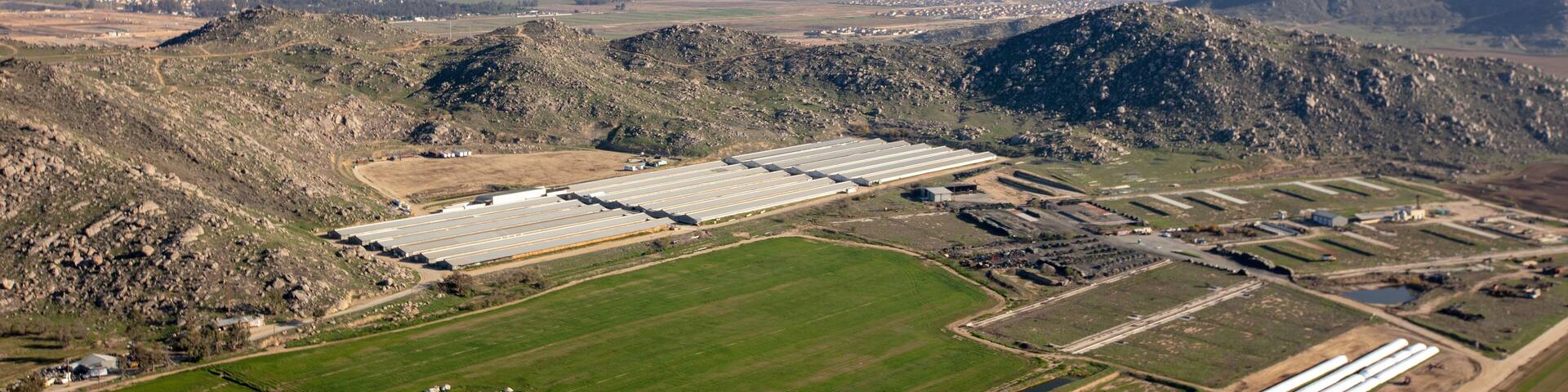 A large industrial facility with multiple warehouses and storage tanks in a mountainous region.