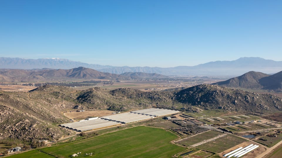 A large industrial facility with multiple warehouses and storage tanks in a mountainous region.