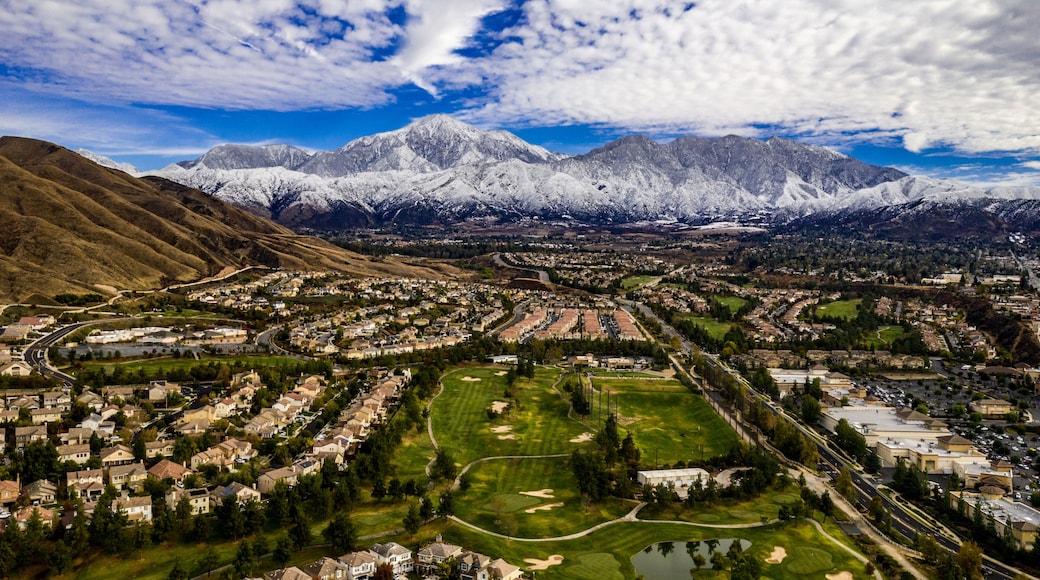 Un pueblo enclavado entre montañas nevadas, con un campo de golf al frente.