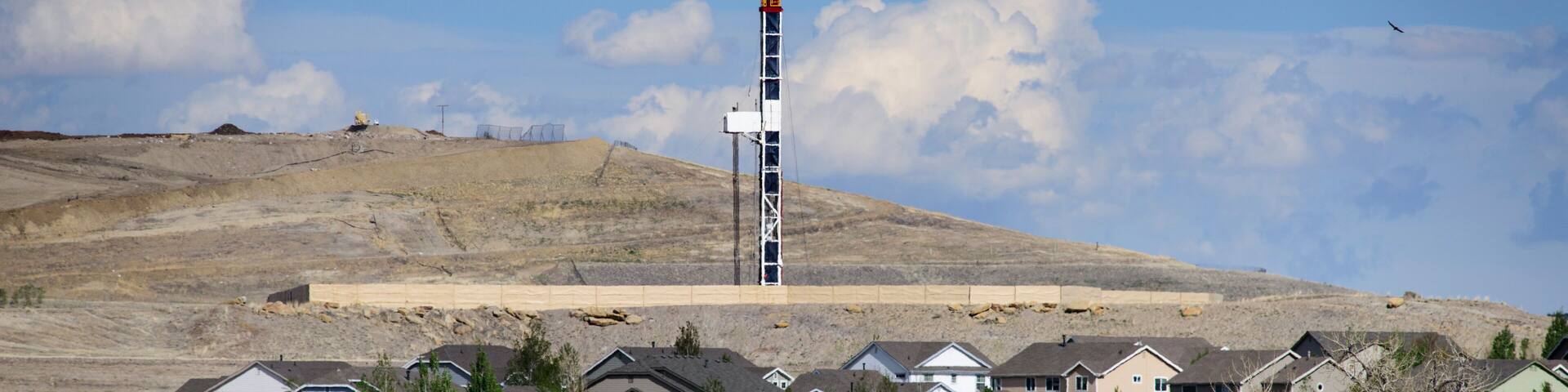 Houses in front of oil and gas drilling operation, Erie, Colorado, USA