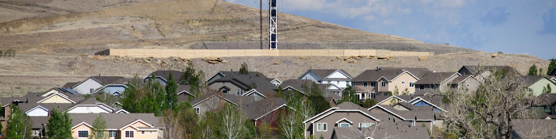 Houses in front of oil and gas drilling operation, Erie, Colorado, USA