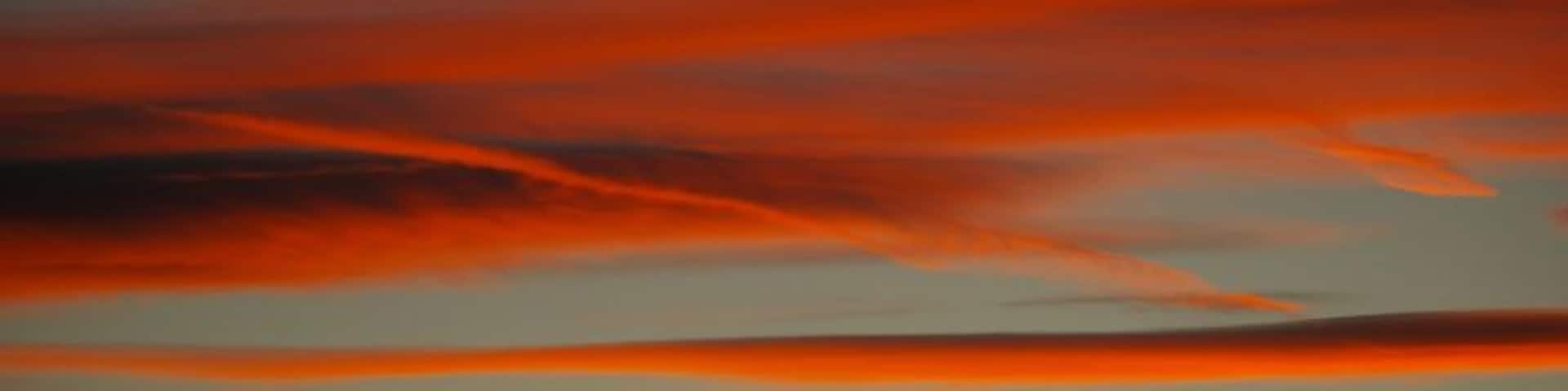 Um pôr do sol com nuvens vermelhas sobre uma cordilheira.