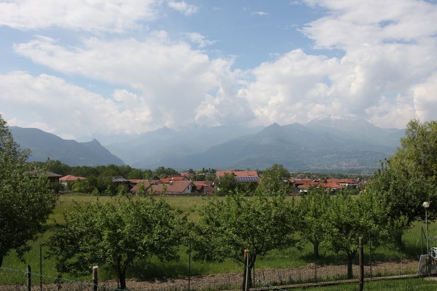 A rural landscape with a village, mountains, and a clear sky.