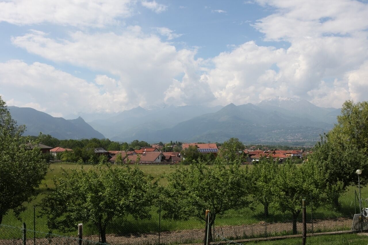 A rural landscape with a village, mountains, and a clear sky.
