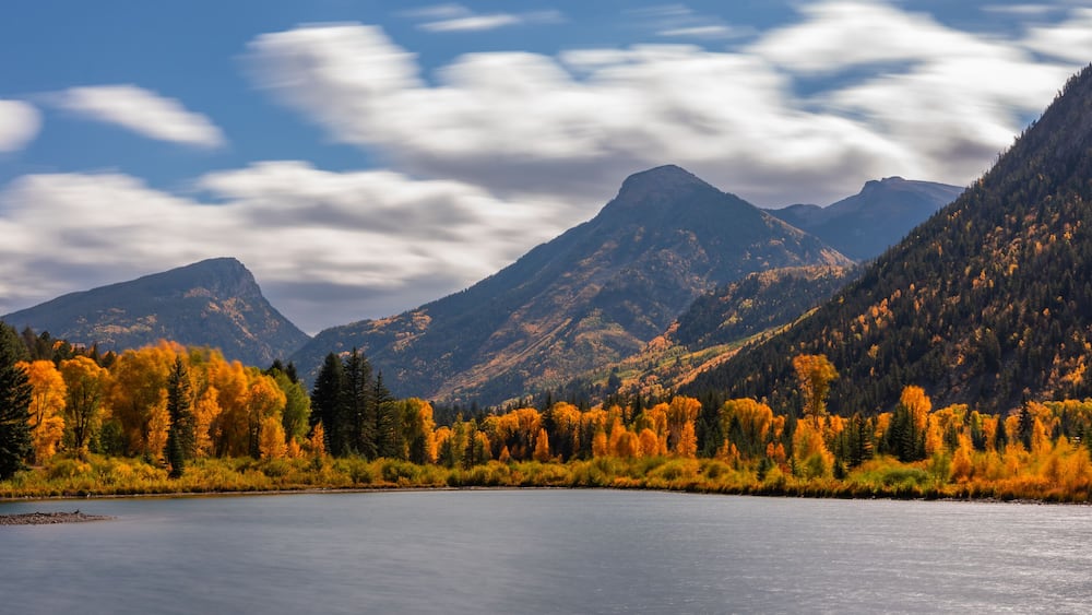 Fast Moving Clouds Over Marble Lake Colorado Autumn Landscape Scene. Bright Blue Sunny Sky with Clouds Over Yellow Aspen Trees.