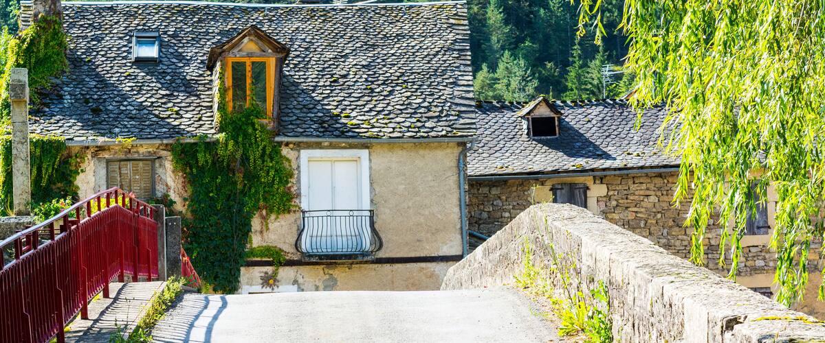 A stone house with a tiled roof, a red bridge, and a stone wall.