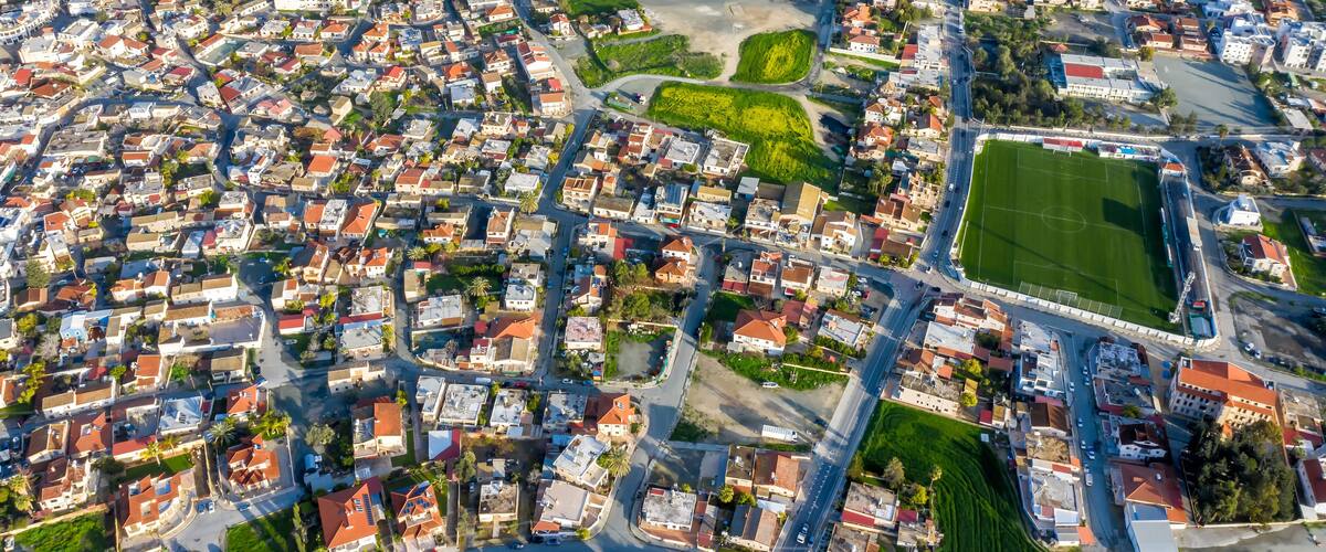 An aerial view of a densely populated urban area with a central green space and a large sports field.