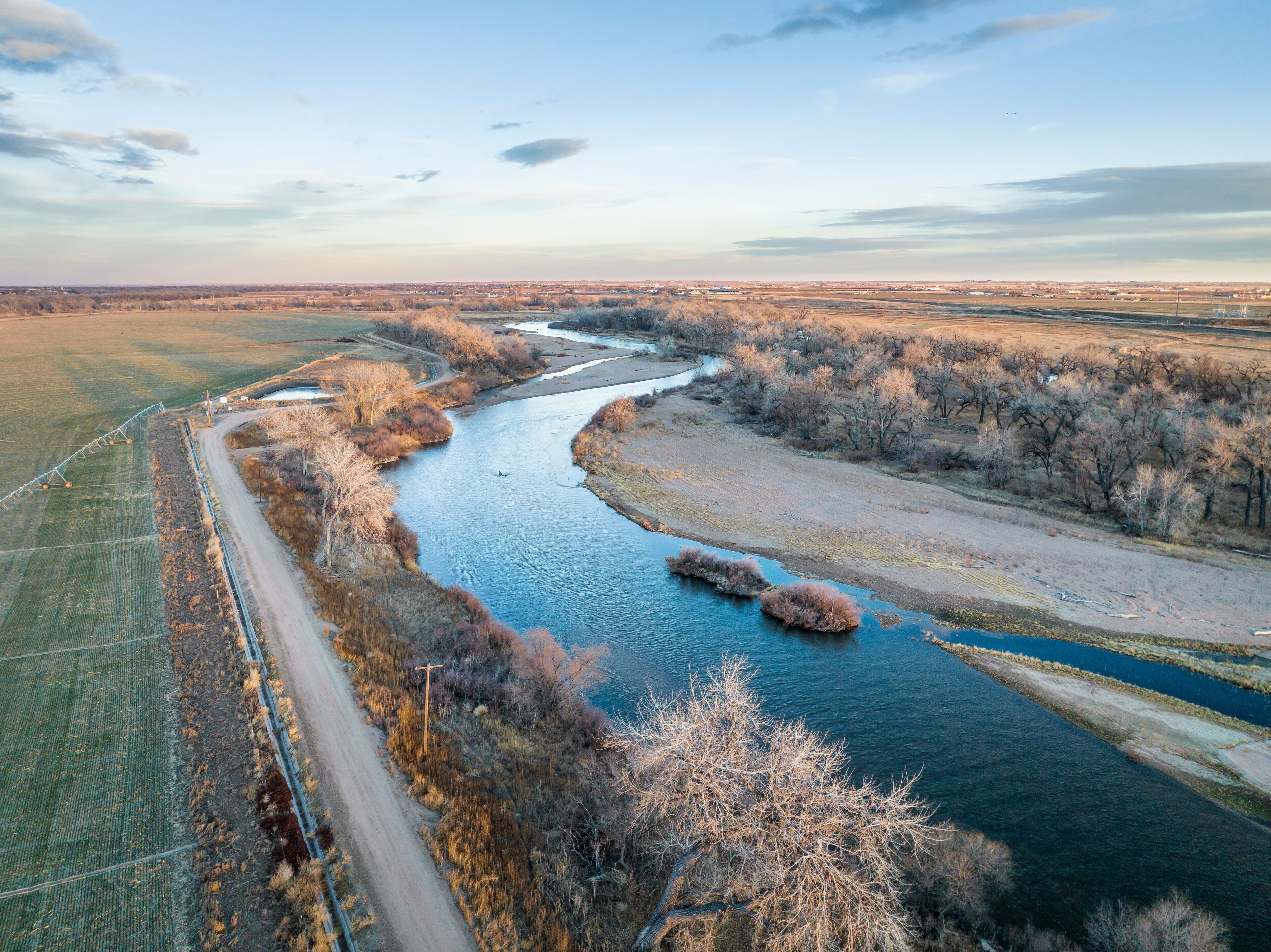 A river winding through a rural landscape with fields and sparse trees.