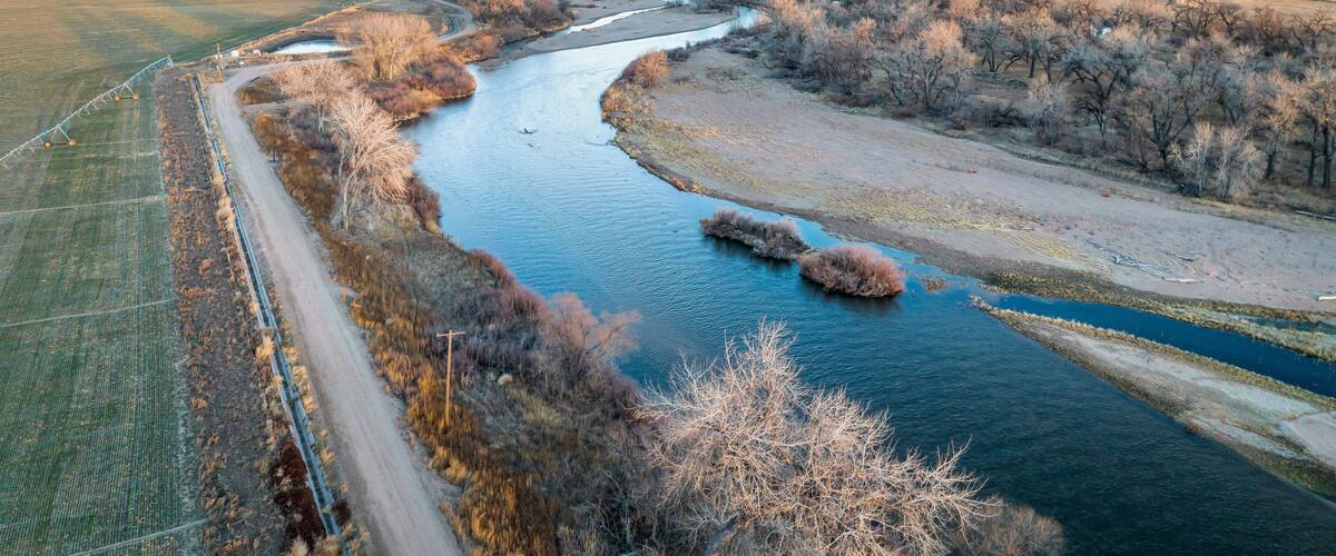 A river winding through a rural landscape with fields and sparse trees.
