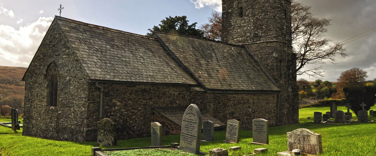 A stone church with a bell tower and a graveyard.