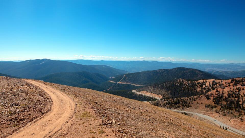 A mountainous landscape with a dirt road winding through the terrain.