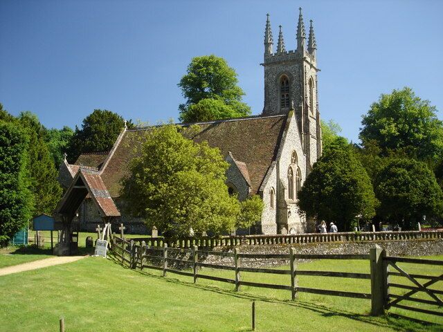 A church with a tall tower and a wooden fence in front.