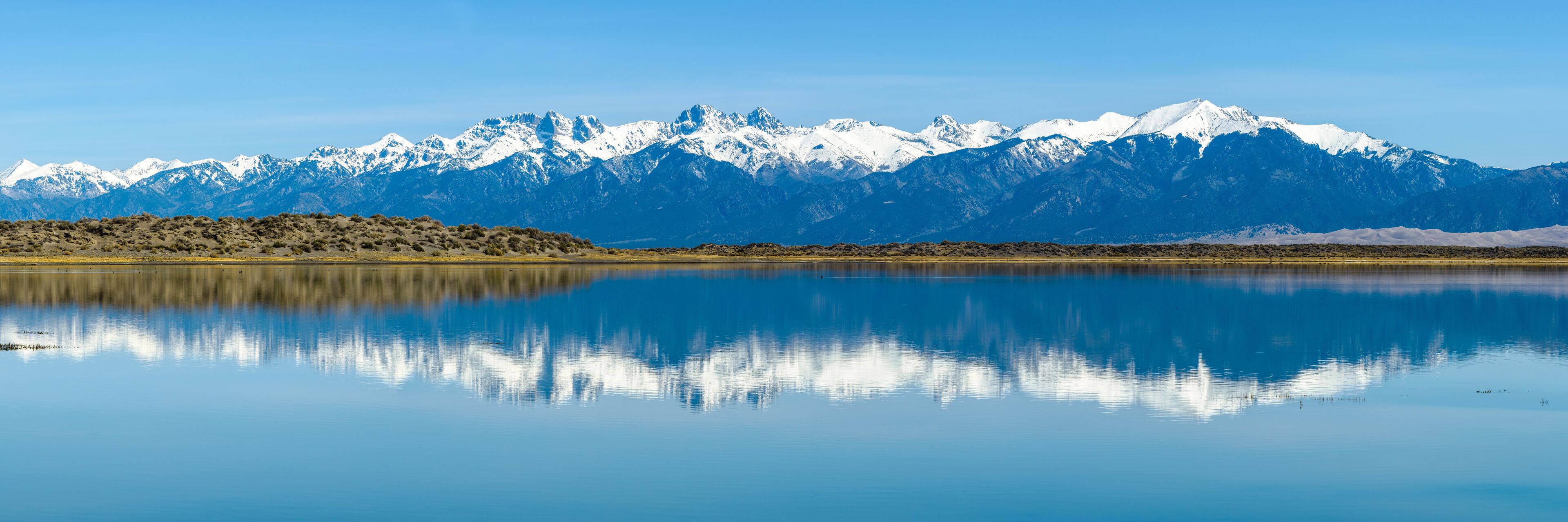 Sangre de Cristo Mountains - Panoramic view of Snow-capped Sangre de Cristo Mountains, reflecting in San Luis Lake. Colorado, USA.