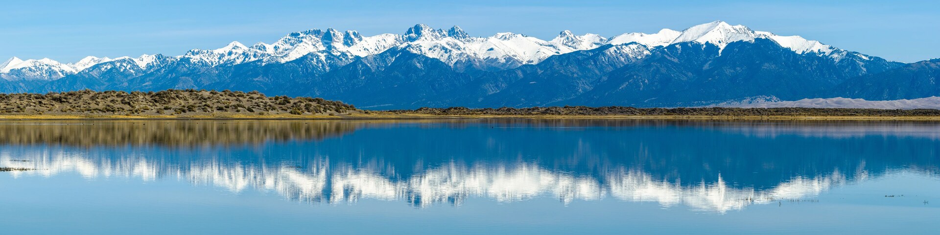 Sangre de Cristo Mountains - Panoramic view of Snow-capped Sangre de Cristo Mountains, reflecting in San Luis Lake. Colorado, USA.