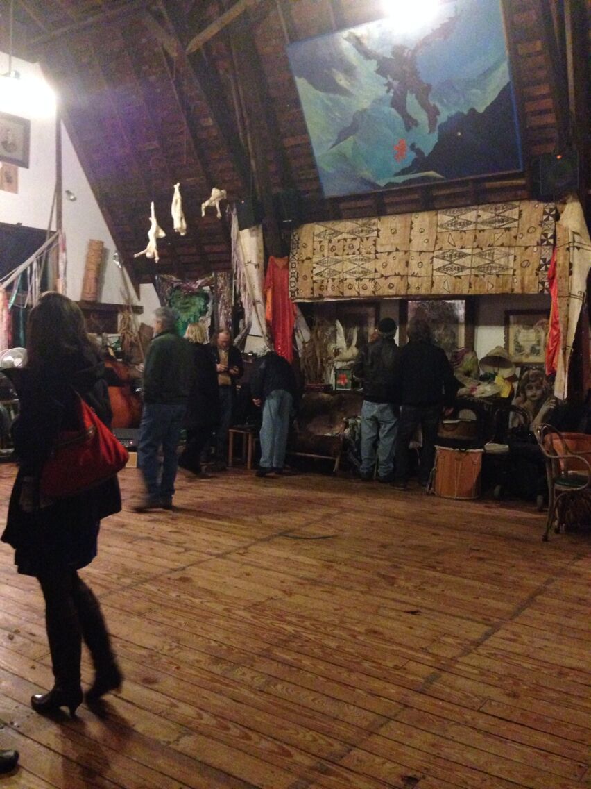 A wooden floor market with people browsing stalls.